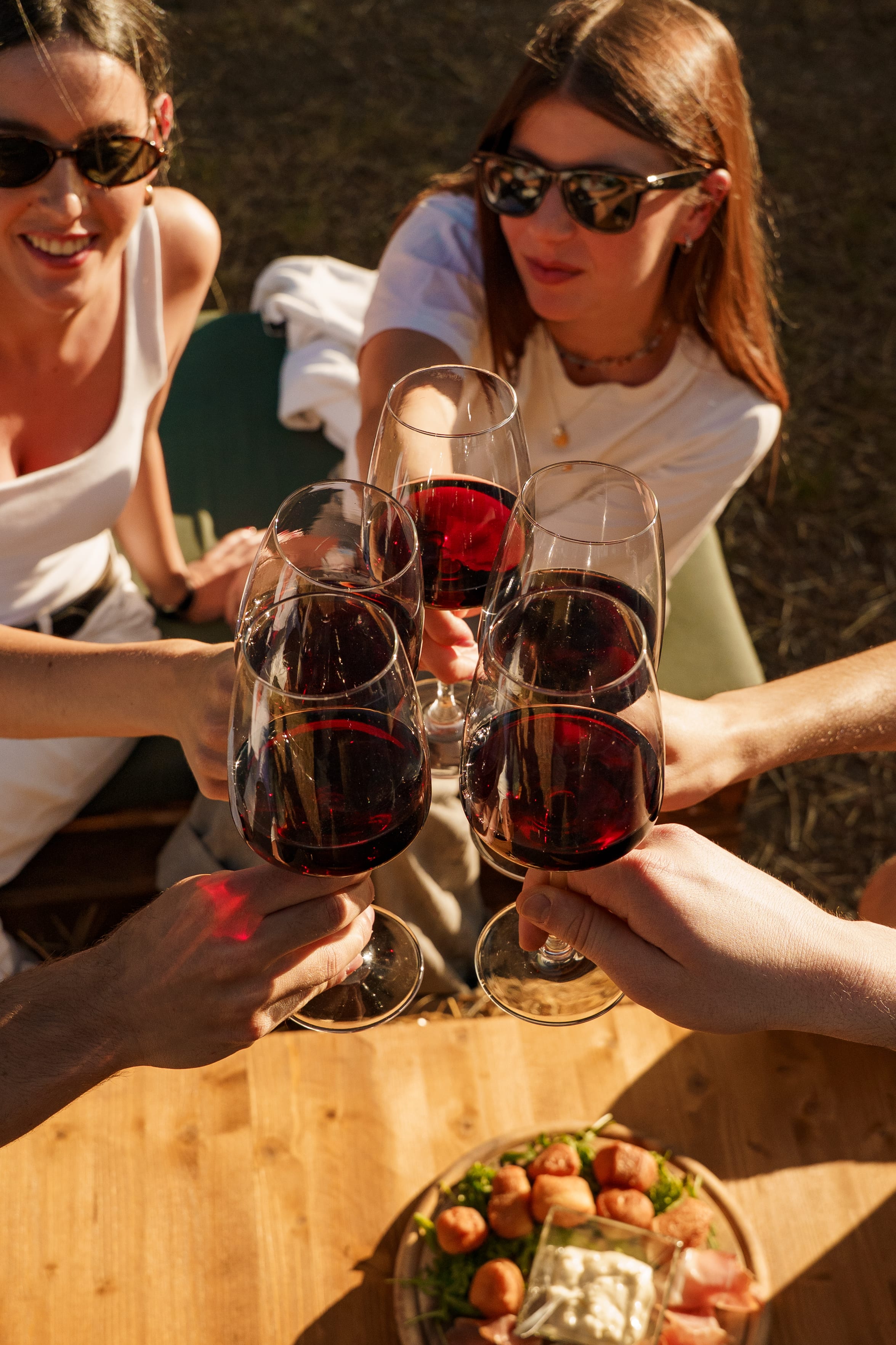 Brindisi con calici di vino rosso al tramonto